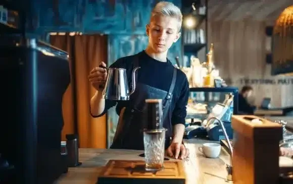 barista pours water from coffee pot into the glass D57H3WU 580x365 1